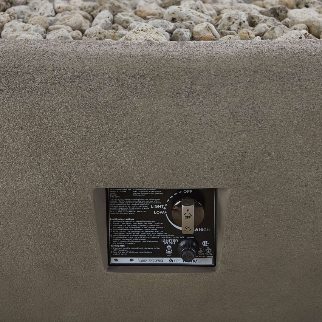 Control panel for a fire pit embedded in concrete with gravel in the background