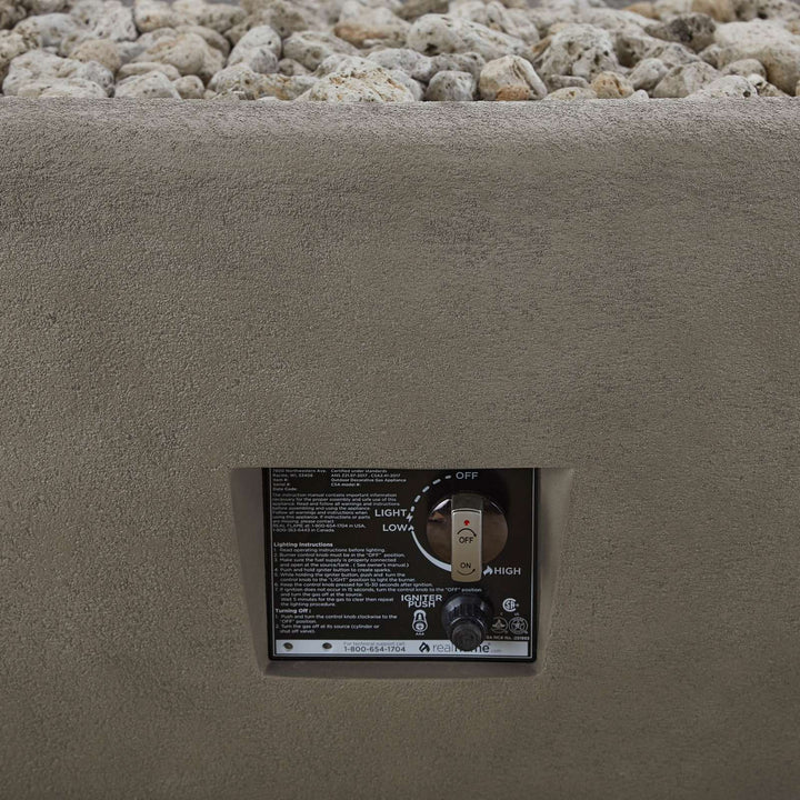 Control panel for a fire pit embedded in concrete with gravel in the background